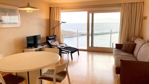Ein modernes Wohnzimmer mit großem Fenster, Fernseher, Sofa und Esstisch.