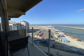 A balcony with a view of a beach, a parking area, and a construction site.