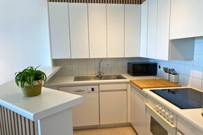 A modern kitchen with white cabinets, a Bosch dishwasher, a microwave, and a wooden countertop. - Apartment in Nieuwpoort with Sea Views (Nieuwpoort)
