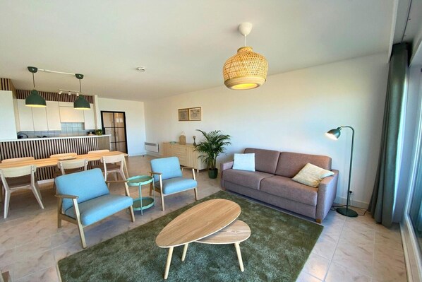 A modern living room with a sofa, chairs, a coffee table, pendant lights, and a hanging light fixture.