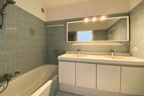 A bathroom with two sinks, a large mirror, and a bathtub.