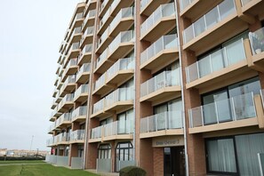 A multi-story building with balconies, a sign reading 'Den Oyer,' and a brick facade.