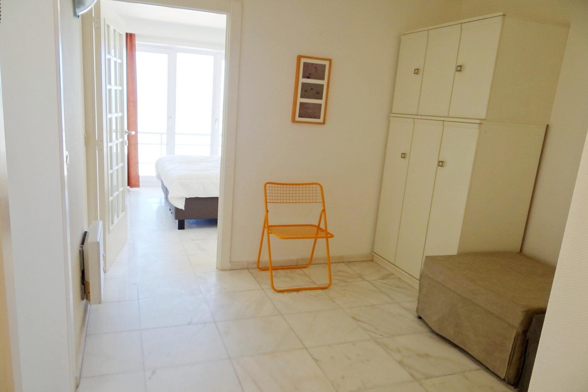 A hotel room with a bed, a chair, a wardrobe, and a small sofa.