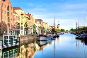 A canal with boats docked, historic buildings, and a windmill in the background. - Apartment near Marina Nieuwpoort (Nieuwpoort)
