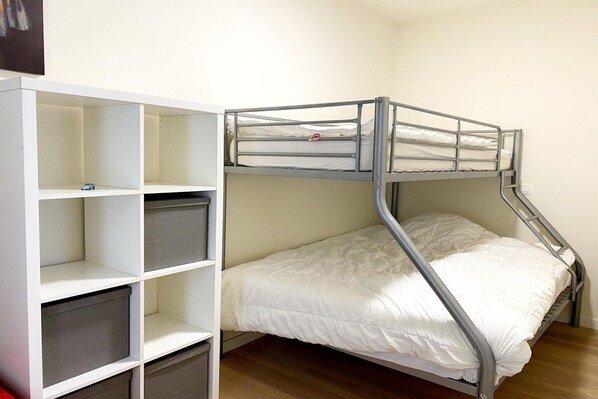 Un lit superposé avec des tiroirs de rangement et une tête de lit blanche.