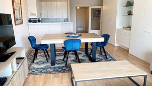 A modern kitchen with white cabinets, a wooden dining table, and blue chairs. - Nieuwpoort Apartment near Sandy Beaches (Nieuwpoort)