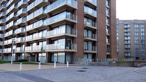 A multi-story residential building with balconies, a paved courtyard, and a sign indicating the building name. - Nieuwpoort Apartment near Sandy Beaches (Nieuwpoort)