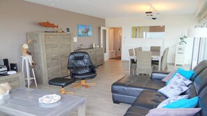 Una sala de estar moderna con un sofá de cuero, una mesa de centro de vidrio y una zona de comedor con mesa y sillas.
