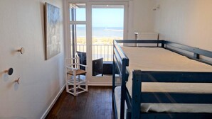 A room with a bunk bed, a chair, a painting, and a view of the beach and ocean through a glass door. - Nieuwpoort Central Retreat (Nieuwpoort)