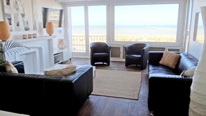 A living room with a view of the beach, a fireplace, and black leather sofas. - Nieuwpoort Central Retreat (Nieuwpoort)