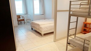 Une chambre avec un lit superposé, un bureau et deux chaises.