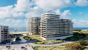 Un hôtel moderne à plusieurs étages, surmonté d’un drapeau, et offrant une vue sur la mer.
