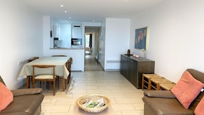 Una sala de estar moderna con comedor, una cocina al fondo y un pasillo que conduce a otra habitación.
