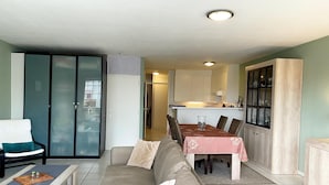 Un salon moderne avec un canapé, une table à manger et des chaises, et un coin cuisine à l’arrière-plan.