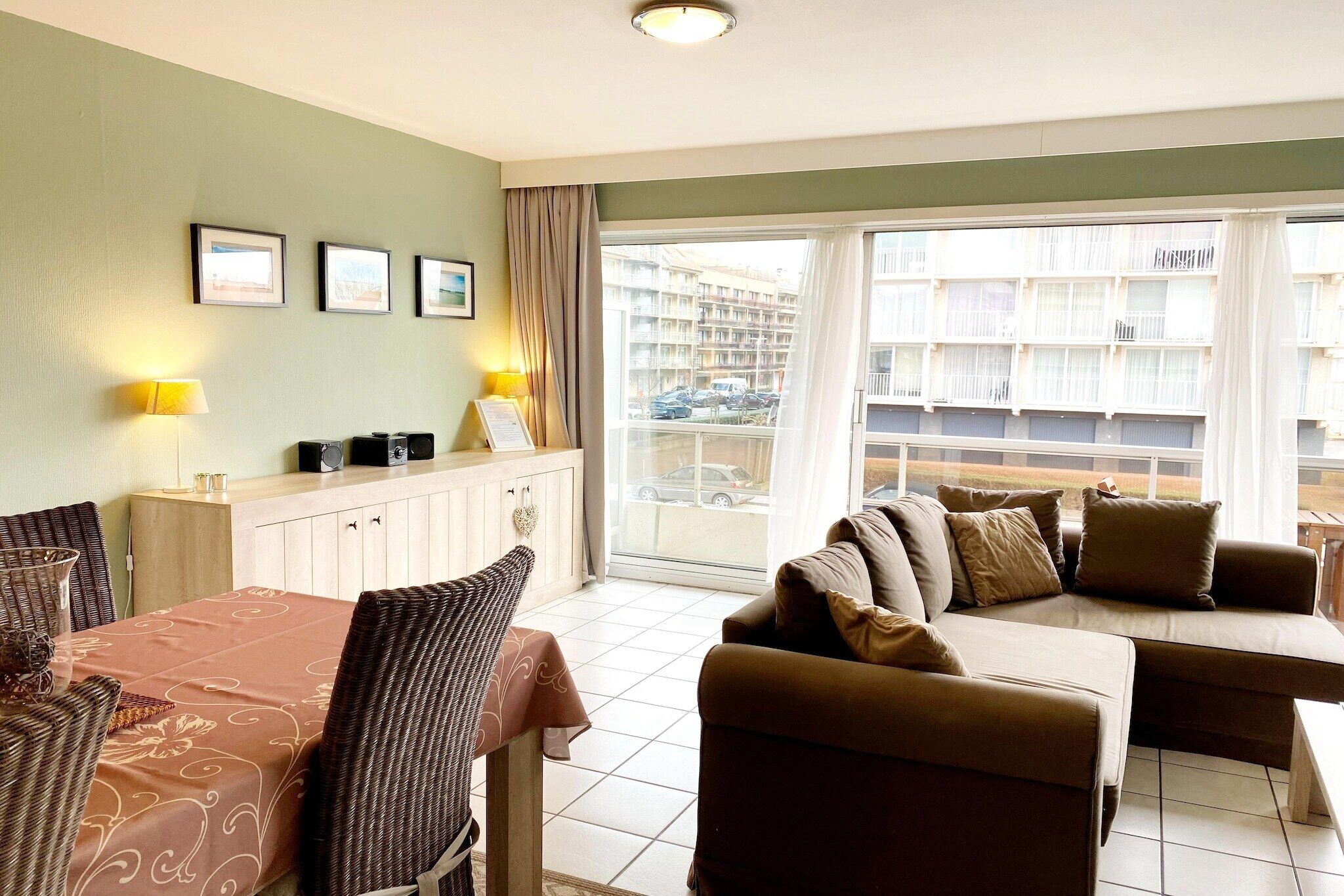 Une chambre d’hôtel comprenant un coin repas, un canapé et donnant sur un immeuble doté de balcons.