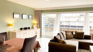 Une chambre d’hôtel comprenant un coin repas, un canapé et donnant sur un immeuble doté de balcons.
