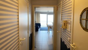 A hallway with striped walls leading to a room with a bed, a desk, and a window. - Apartment in Nieuwpoort with Ocean Views (Nieuwpoort)