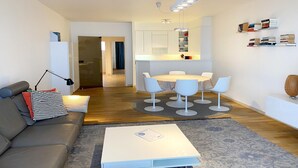 A modern living room with a sofa, coffee table, and a dining area with a table and chairs. - Apartment in Nieuwpoort with Sea Views (Nieuwpoort)
