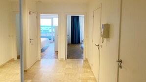 A hotel hallway with a view to a balcony, a door with a lock, and a light switch on the wall. - Apartment in Nieuwpoort with Sea Views (Nieuwpoort)