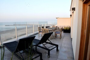 Un balcon donnant sur la mer, aménagé avec des chaises et une table.