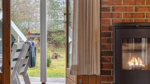 A cozy room with a fireplace, a wooden bench, and a view of the outdoors. - "Sofja" - 175m to the fjord by Interhome (Hadsund)