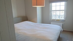 A bedroom with a single bed, a window with a view, and a lamp. - Apartment in Nieuwpoort near the Beach (Nieuwpoort)