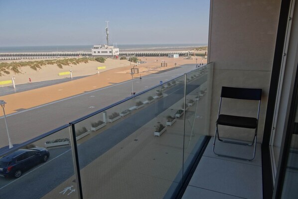 Ein Balkon mit Blick auf einen Strand, eine Straße und ein Gebäude in der Ferne.