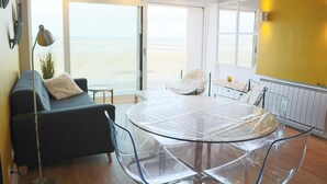 Un salon moderne avec une table en verre, un canapé et une vue sur la plage.