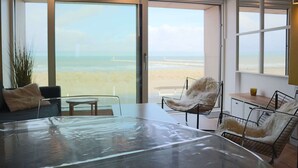Une chambre moderne avec de grandes fenêtres, une table en verre et une vue sur la plage.