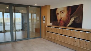 Un hall d’entrée avec une porte vitrée, un banc en bois doté de casiers et un grand portrait accroché au mur.