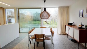A modern kitchen with a large dining table, chairs, and a pendant light. - Apartment in Nieuwpoort by Beach (Koksijde)