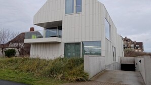 A modern two-story building with a flat roof, large windows, and a visible balcony. - Apartment in Nieuwpoort by Beach (Koksijde)