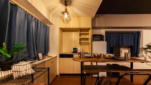 Cocina compacta con comedor, que incluye un microondas integrado, hervidor y cafetera.