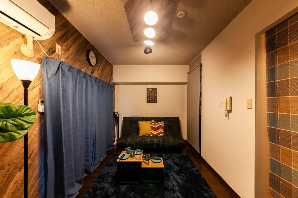 A compact living space with a sofa, a small coffee table, and a wall-mounted clock.