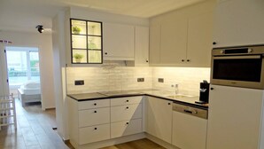 Een moderne keuken met witte kasten, een inbouwoven en een vaatwasser.