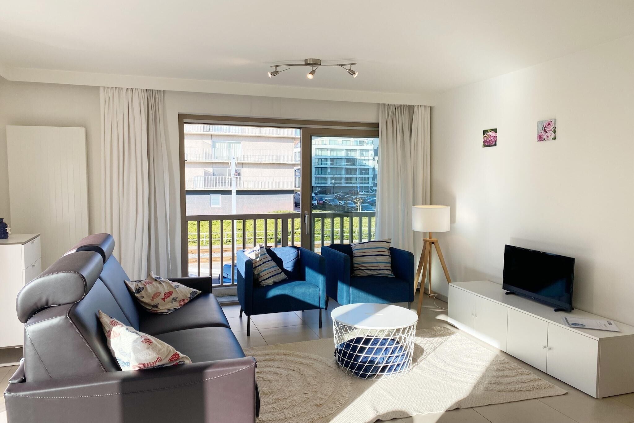 A modern living room with a sofa, two armchairs, a TV, and a balcony with a view of buildings.