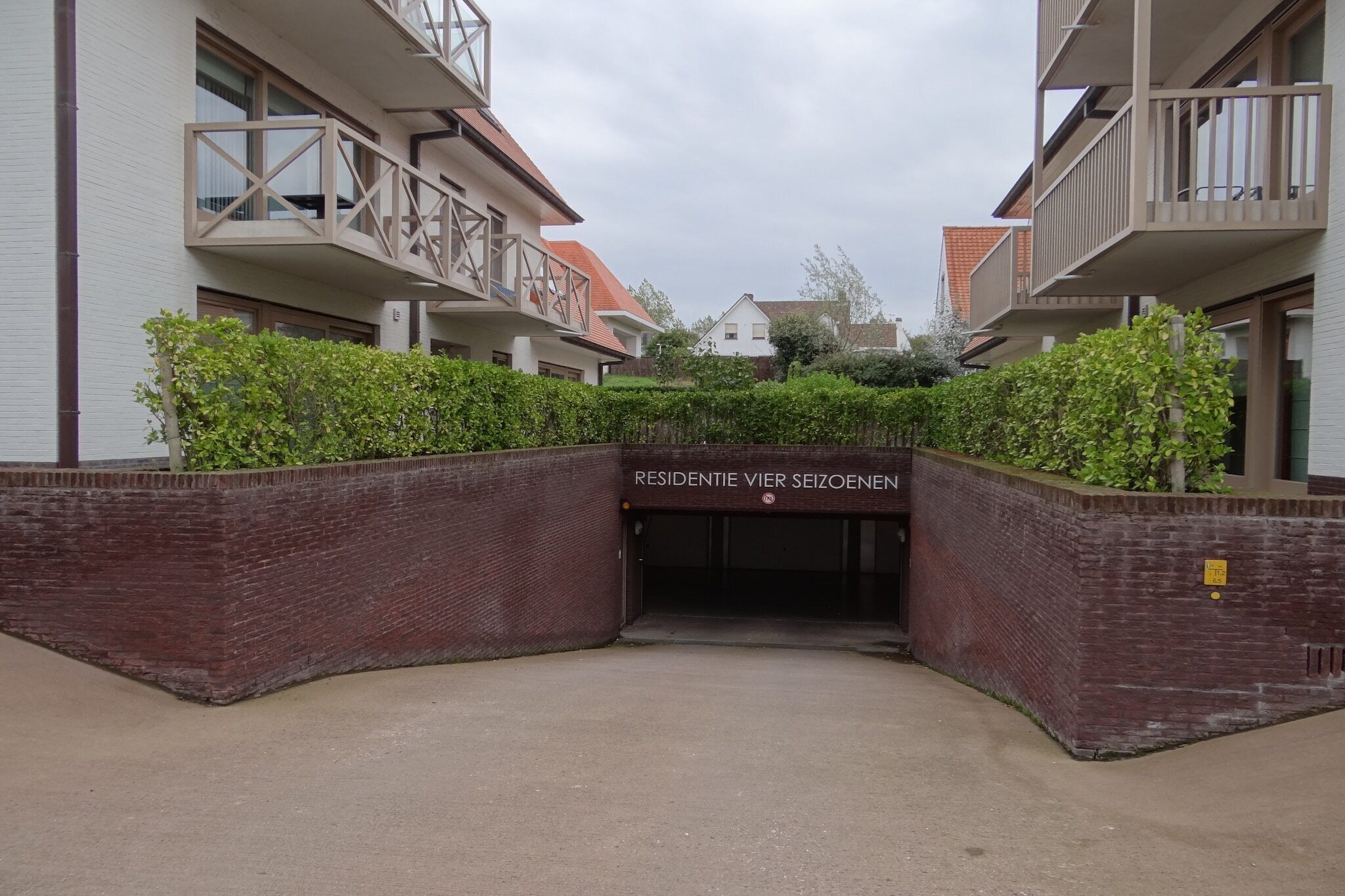 Een woongebouw met een hekpoort, bakstenen muren en een bord met de naam erop.
