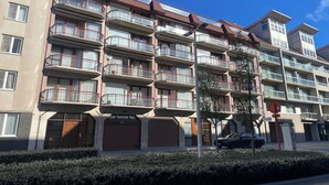 A multi-story residential building with balconies, a garage, and a street view. - Apartment in Nieuwpoort near the Beach (Nieuwpoort)