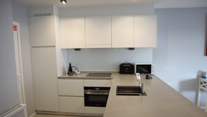 A modern kitchen with white cabinets, a built-in oven, and a sink.