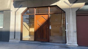 A modern building entrance with a large glass door and a wooden door.