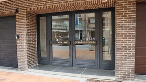Une entrée d’immeuble avec une façade en briques et une grande porte vitrée.