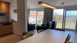 A modern kitchen with a microwave, dishwasher, and a dining area with a table and chairs.
