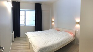 A bedroom with a bed, a window with curtains, and wall-mounted lights. - Apartment in Nieuwpoort by Sandy Beaches (Nieuwpoort)