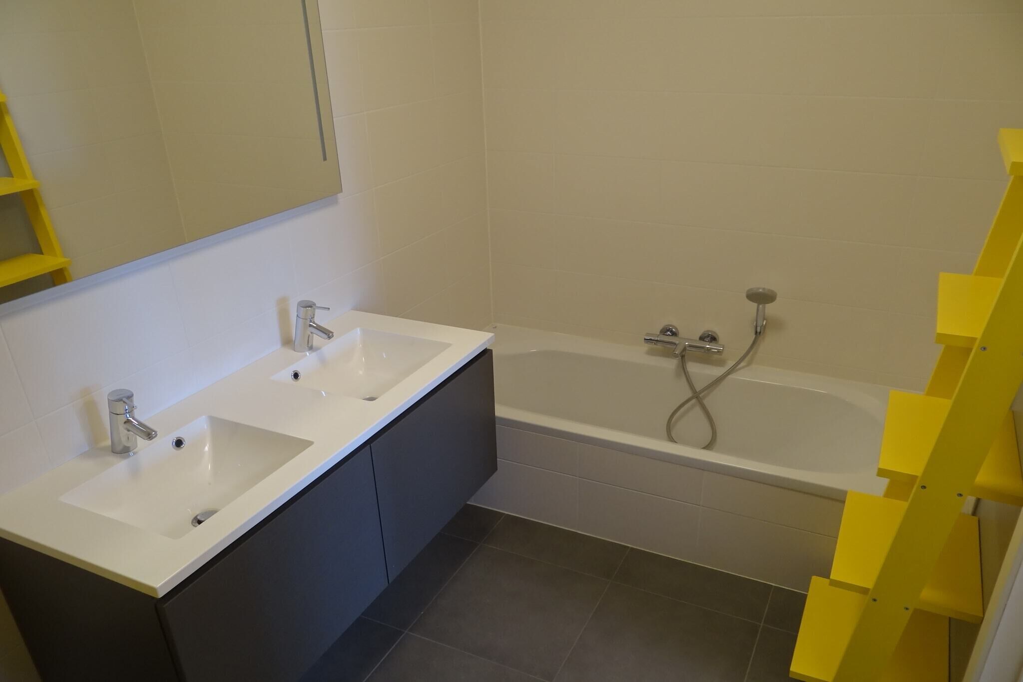 A bathroom with two sinks, a bathtub, and a yellow ladder.