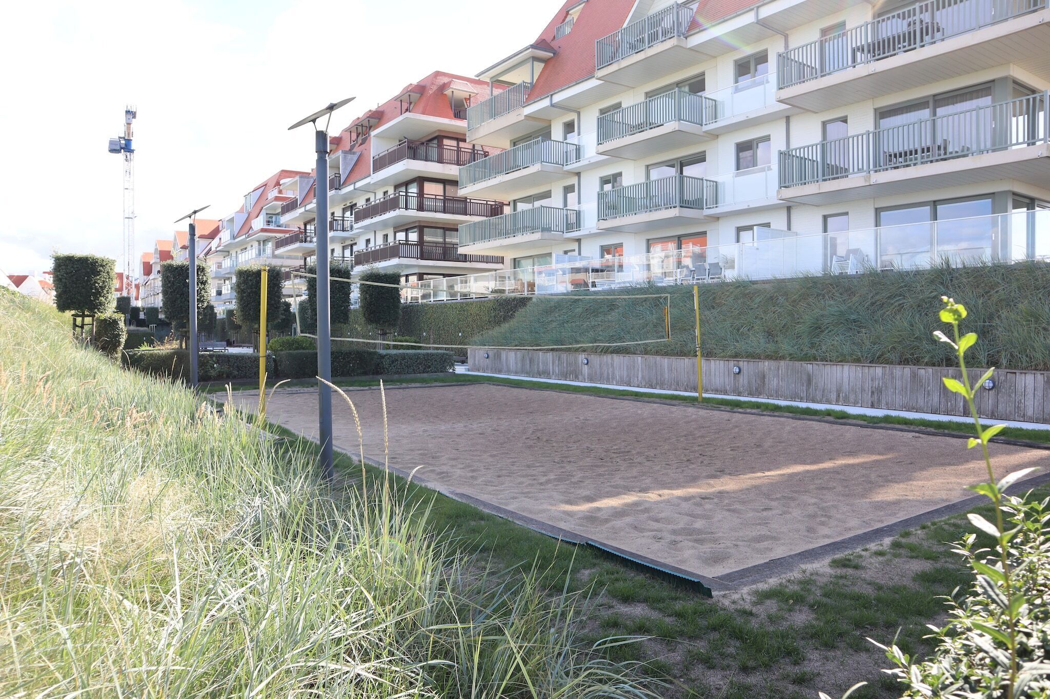 Zona residencial com edifícios altos, um pátio de areia e uma cerca de madeira.