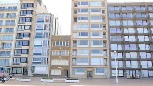 Une rangée d’immeubles résidentiels à plusieurs étages dotés de balcons, un bâtiment central au style architectural particulier et un lampadaire au premier plan.