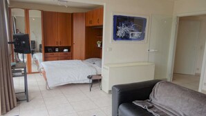 Une chambre à coucher comprenant un lit, un bureau, une chaise, une armoire et une salle de bain.