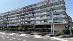 Un hôtel à plusieurs étages, doté de balcons, d’un parking et d’une voie ferrée en premier plan.
