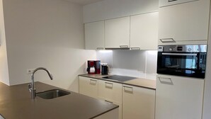A modern kitchen with a stainless steel sink, a Bosch oven, and a coffee maker.
