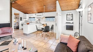 Eine moderne Küche mit weißen Schränken, einer zentralen Kochinsel und einem Essbereich mit Tisch und Stühlen.